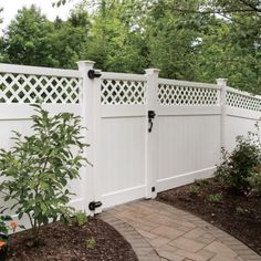 a white fence with black hardware on the top and bottom part, along with brick walkway