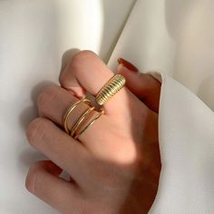 a woman's hand wearing a gold ring with two rings on the middle of it