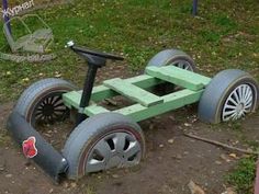 an old wooden toy car with wheels and spokes on the ground in front of a playground