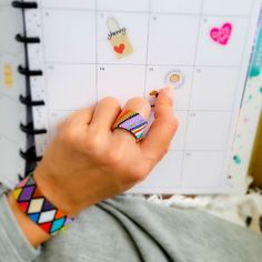 a person holding a planner with stickers on it and a pen in their hand