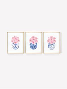 three blue and white vases with pink flowers on them are hanging in front of a wall