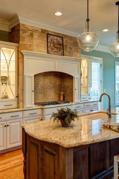 a large kitchen with an island in the middle and marble counter tops on both sides