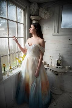 a woman standing in front of a window with her hand on the window sill