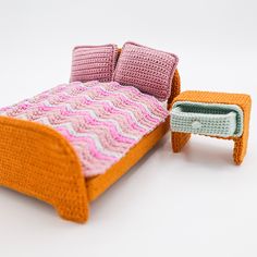 a crocheted bed and small table on a white surface