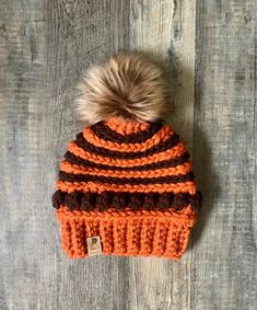 an orange and brown knitted hat with a pom - pom on top