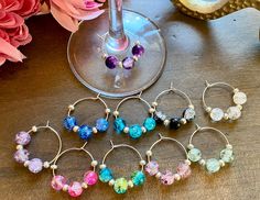 six wine glass charms sitting on top of a table next to a vase with flowers