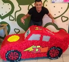 a man standing next to a cake shaped like a car