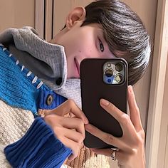 a person taking a selfie with their cell phone in front of her face and wearing a sweater