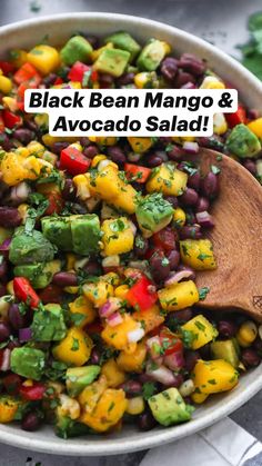 black bean mango and avocado salad in a bowl with a wooden spoon