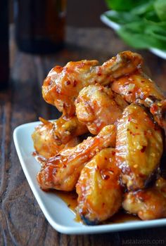 a white plate topped with chicken wings covered in sauce