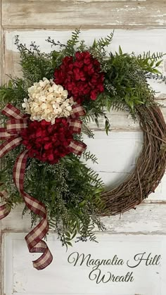 a wreath with red and white flowers is hanging on a wooden wall next to the words magnolia hill wreath