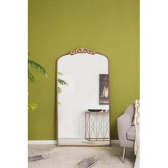 a mirror sitting on top of a white table next to a chair and potted plant