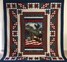 an american flag and eagle quilt hanging on a wall