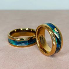 two gold wedding bands with blue and green marbled inlays on each band