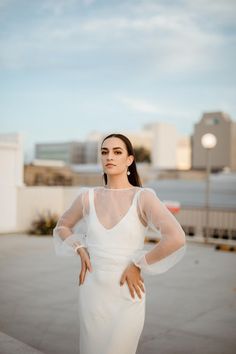 a woman in a white dress is posing for the camera with her hands on her hips