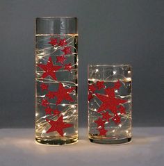 two glass vases with red stars on them and one is filled with clear water