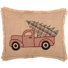 a red truck with a christmas tree on it's back is sitting in front of a burlap pillow