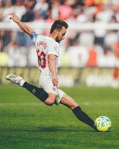 a man kicking a soccer ball on top of a field