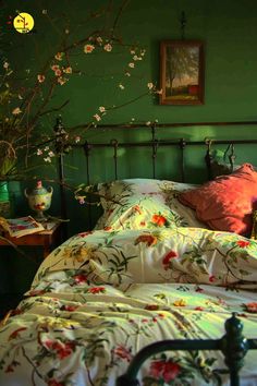 a bedroom with green walls and flowers on the bed, along with an iron headboard