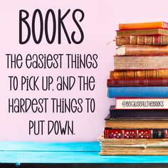 a stack of books sitting on top of a blue table next to a pink wall