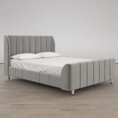 an upholstered bed with white sheets and pillows in a minimalistic bedroom setting