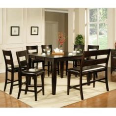 a dining room table and chairs in front of a window with an area rug on the floor