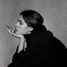 a black and white photo of a woman with her hand on her chin looking to the side