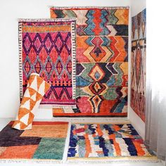 an assortment of colorful rugs on display in a room with white walls and flooring