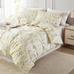 a bed with white sheets and yellow flowers on the comforter is in a bedroom