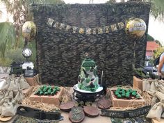 a table topped with lots of cakes covered in green frosting and surrounded by army decorations