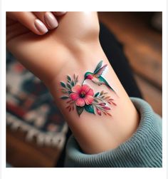 a woman's wrist tattoo with pink flowers and hummings on it, while the rest of her arm is visible