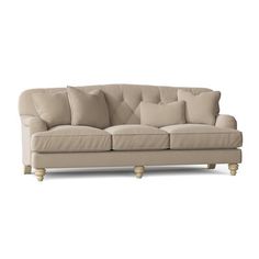 a beige couch with several pillows on the armrests and one pillow sitting on top of it