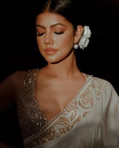 a woman in a white sari with a flower in her hair and eyes closed