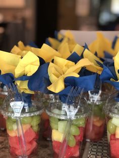 small cups filled with different types of fruit on top of a wooden table covered in blue and yellow streamers