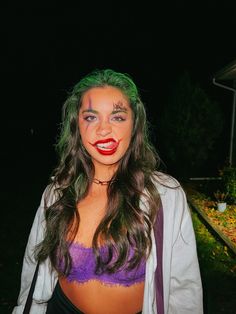 a woman with green hair and makeup is posing for the camera in front of a house