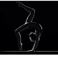 a man doing a handstand in the dark with his arms stretched out and feet bent