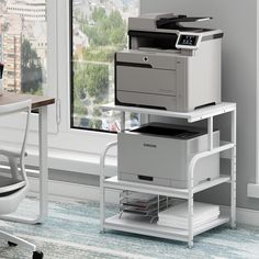 an office desk with printer and scanners on it in front of a large window