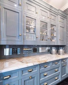 a kitchen with gray cabinets and marble counter tops, gold pulls on the cupboards