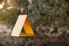 a yellow bird feeder hanging from a tree