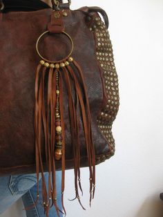 a brown leather purse with tassels hanging from it