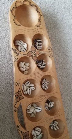 a wooden tray filled with lots of nuts on top of a carpeted floor next to a spoon