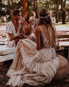 three women sitting on the ground in dresses