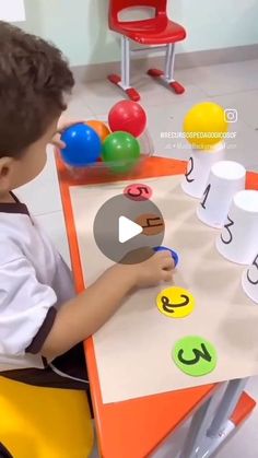 a little boy sitting at a table playing with letters and numbers on the same board