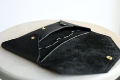 "This is a envelope clutch wallet, handcrafted in the heart of Colorado. Dimensions: 8.25\" wide, 4.5\" tall This wallet clutch is a perfect mixture of elegance and utility. The intriguing folded design, shows off the beautiful curves of the leather and also allow the clutch to easily hold your phone in the main compartment. There are three internal credit card slots with thumb tabs, and a special pocket designed to fit a passport, cash and other paper bits that you need. The leather has a beaut Black Envelope Clutch With Card Slots, Black Envelope Wallet As A Gift, Envelope Clutch With Interior Card Slots As Gift, Modern Clutch With Interior Card Slots For Gift, Modern Clutch With Interior Card Slots As Gift, Gift Clutch With Interior Card Slots, Everyday Envelope Clutch, Black Clutch With Interior Card Slots As Gift, Leather Clutch With Magnetic Closure For Gift