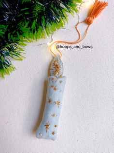 an ornament hanging from a christmas tree on a white surface with green branches