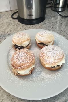 four pastries sitting on a plate next to an electric crockpot and coffee pot