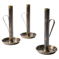 three metal candlesticks and one candle holder in the shape of a boat on a white background