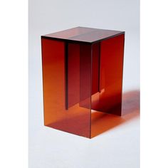 a red glass table sitting on top of a white floor next to an orange wall