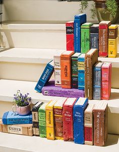 a stack of books sitting on top of a set of steps next to a potted plant