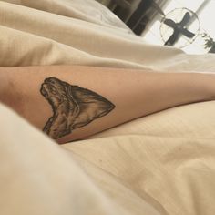 a person laying in bed with a tattoo on their leg